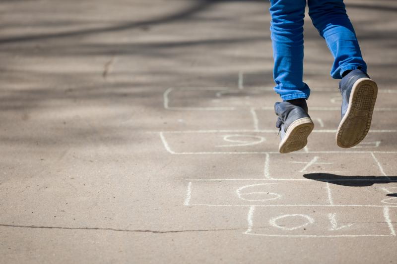Child jumping on hopscotch numbers