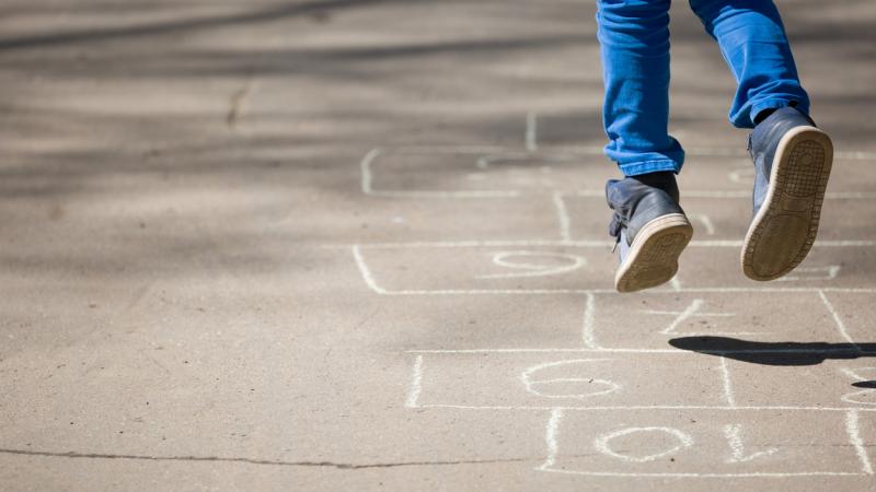 Child jumping on hopscotch numbers